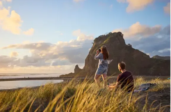 People sitting on the top of a sand dune looking out over the ocean People sitting on the top of a sand dune looking out over the ocean